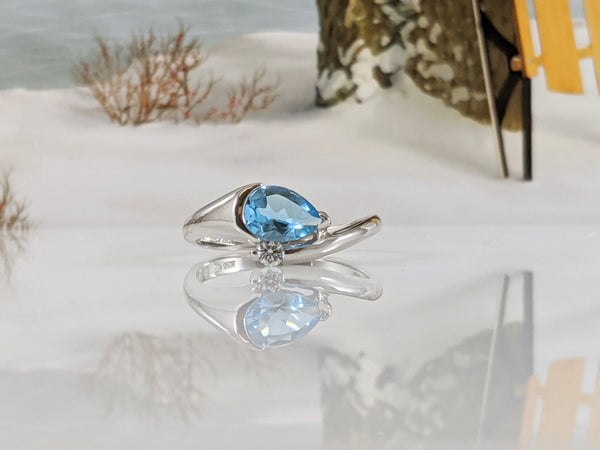 10K white gold ring with a lovely 7x5mm pear shape blue topaz. A single .02ct round brilliant cut diamond accents this stunning piece. Finger size 6  $670.00