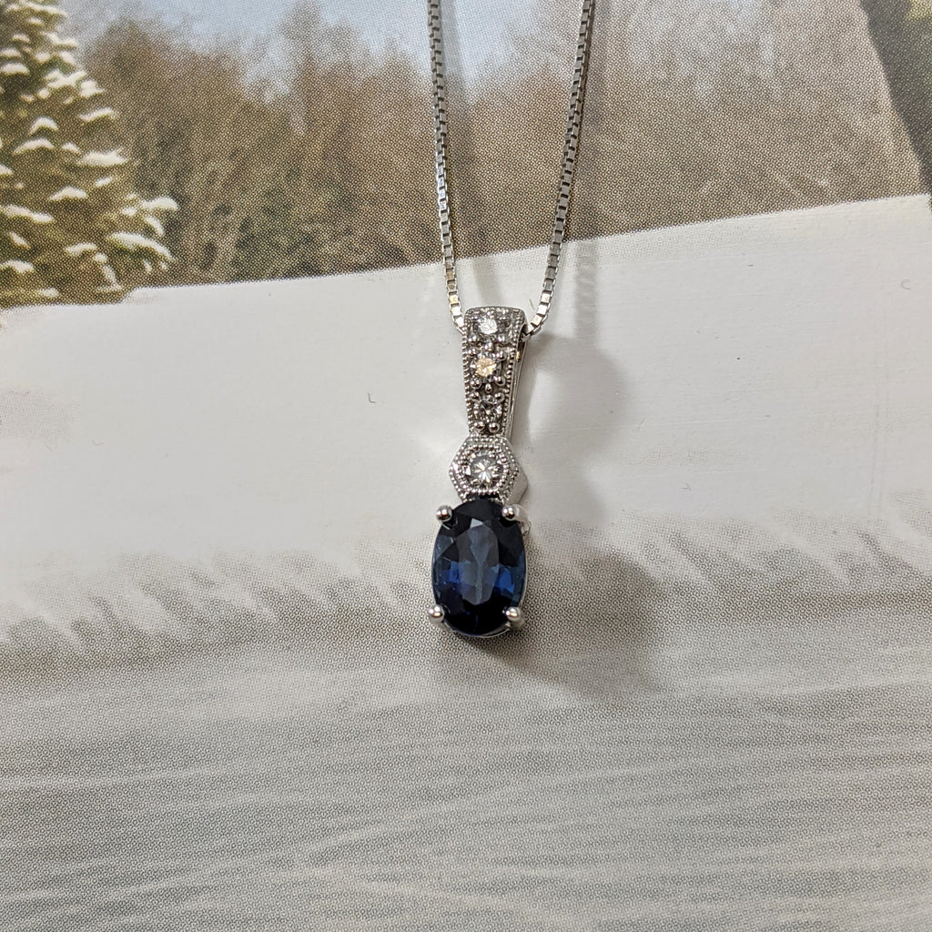 14k white gold natural 6x4mm blue Sapphire pendant. Set with .16cttw in round brilliant cut diamonds in a beautiful design. Chain sold separately. $550.00