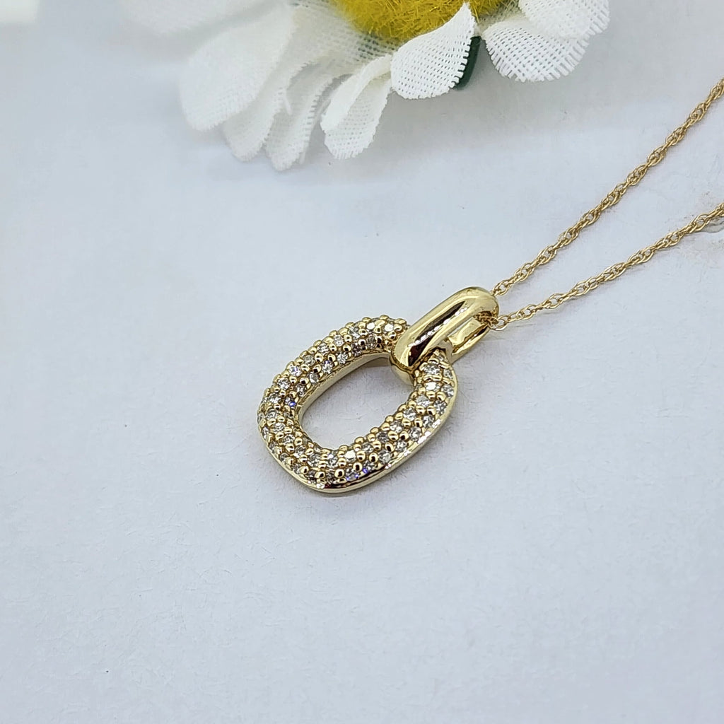 This beautiful pendant is made from 10K yellow gold and is set with 1/5th of a carat total weight in natural mined round brilliant cut diamonds. Including the high polish bail, this piece measures 16.26mm in length and 9.55mm in width. The pendant is hung on an 18 inch chain