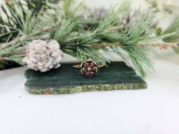 This beautiful estate ring is made from 10k yellow gold and is set with (5) five small natural rubies and (1) one diamond in the center. Beautifully constructed, the ring top is designed as a flower with the rubies and a diamond as the center. The ring weighs 3.2 grams including the stones. The ring measures 10.46mm across the top. The shoulders and shank measure 1.88mm tapering to 1.65mm

*This is an estate item. Estate items have been refurbished but may show slight wear. Sizing not included