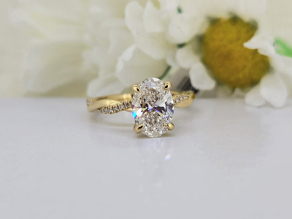 14k yellow gold diamond engagement ring set with a 2.03ct lab grown oval diamond in a four prong yellow gold head. The mounting is a twist of high polish gold and an 1/8th of a carat in round brilliant cut diamonds. All diamonds are D-E in color and VS1 in clarity. 
