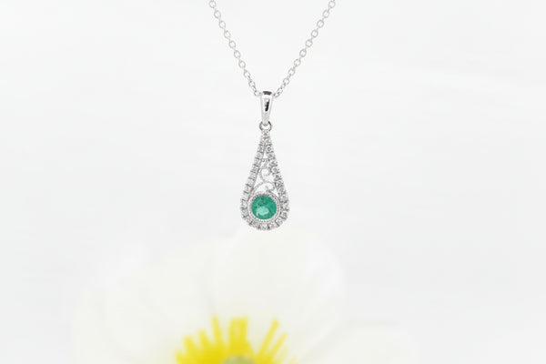 This graceful pendant is crafted in 14k white gold and features a 4.00mm round cut natural emerald at its center. The lively green emerald is accented by .15 carat total weight of natural mined diamonds, adding elegant sparkle and highlighting the pendant’s delicate openwork design.

The pendant is suspended from an 18-inch 14k white gold Singapore chain, offering a soft shimmer and comfortable everyday wear.

A timeless piece that blends classic color with refined detail.
