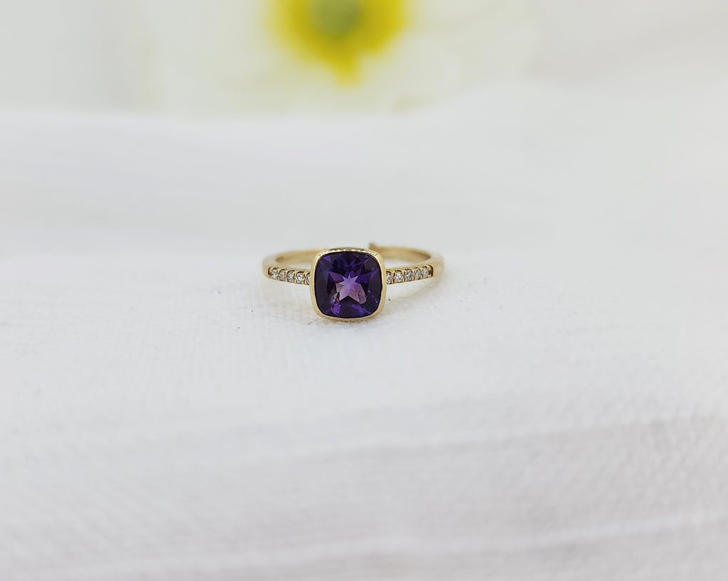 Gold ring with a purple gemstone on a white background