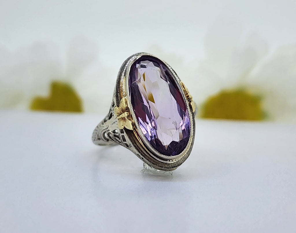 14K White gold filigree ring with 14K yellow gold butterfly accents features a 17.50mmx9.00mm Amethyst. The ring measures 20.83mm at the top and tapers to a 1.80mm shank. *This is an estate ring. Stone size is approximate. Stone does show some abrasion