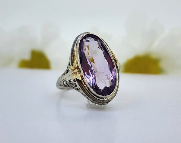 14K White gold filigree ring with 14K yellow gold butterfly accents features a 17.50mmx9.00mm Amethyst. The ring measures 20.83mm at the top and tapers to a 1.80mm shank. *This is an estate ring. Stone size is approximate. Stone does show some abrasion