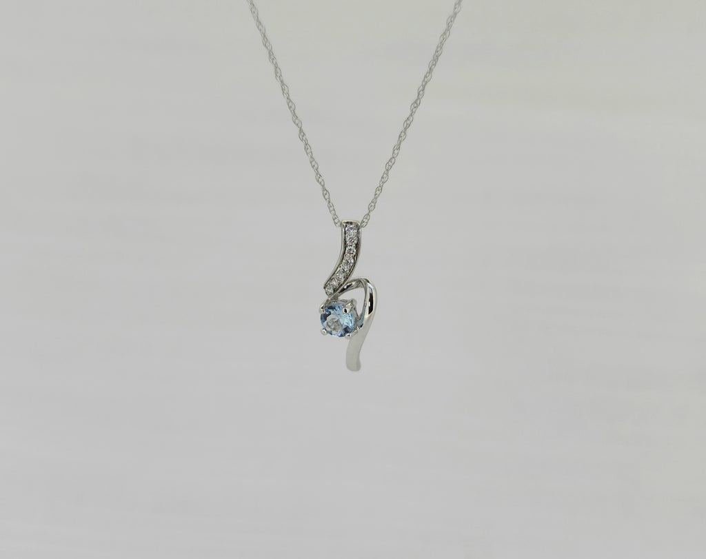 Gracefully contoured, this pendant features a natural 4mm round sky blue topaz, admired for its kiss of blue hue and gentle sparkle. The center stone is cradled within a flowing 14K white gold design, accented by .06 carat total weight of natural mined round brilliant diamonds that add a subtle ribbon of brilliance.
The pendant measures 18.50mm in length and 5.69mm in width, creating a slender, elegant silhouette with beautiful movement. It is suspended from an 18-inch 10K white gold Singapore chain, 