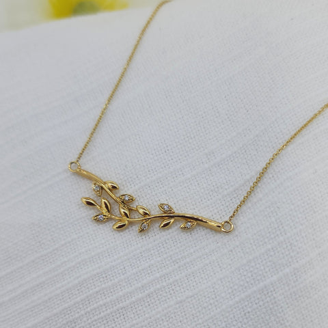 Delicate and graceful, this 14k yellow gold leaf necklace is a timeless symbol of natural beauty. Crafted in warm, rich gold and weighing 3.6 grams, the design features a softly curved branch adorned with leaf motifs, each accented by round brilliant cut natural mined diamonds totaling .05 carat total weight.

 Finished with an adjustable chain that wears beautifully at 16, 17,18 inches
