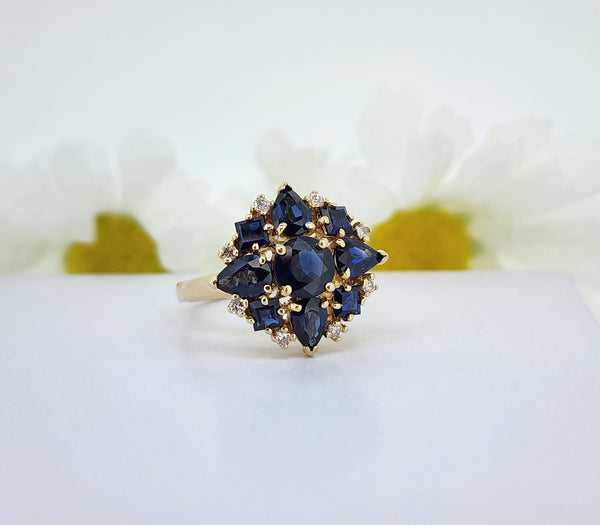 This is quite the lovely Sapphire and Diamond cocktail ring! Beautifully styled using four pear shape, four step cut square and one round diamond cut Sapphire accented by eight round brilliant cut diamonds. The Sapphires favor a midnight blue color. The ring measures 17.63mm at the top and tapers to a 2.19mm shank, Quite lovely indeed!