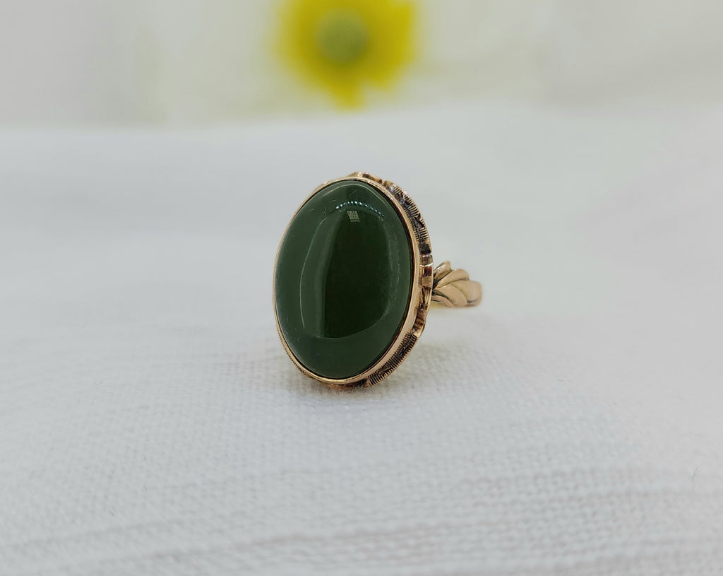 This striking vintage 18K gold ring features a richly colored oval jade cabochon in a classic bezel setting, beautifully framed by an intricate hand-finished gallery visible from the underside. The detailed back design highlights the craftsmanship of the piece and adds distinctive vintage character. The original patina of the gold has been intentionally preserved to maintain its authentic estate charm.
Details:
• 18K gold
• Natural oval jade cabochon
• Measures 20.40mm at the top
• Tapers to a 2.00mm shank