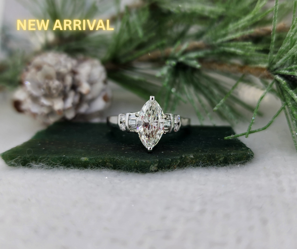 A well built 14k white gold mounting features a 1.16ct natural mined marquise cut center diamond accented by .20cttw in natural mined round brilliant and tapered baguette diamonds. The center diamond is graded by us as being J in color and SI1 in clarity. This diamond currently does not have a certificate. Total diamond weight of this ring is 1.36cttw. Stunning ring!