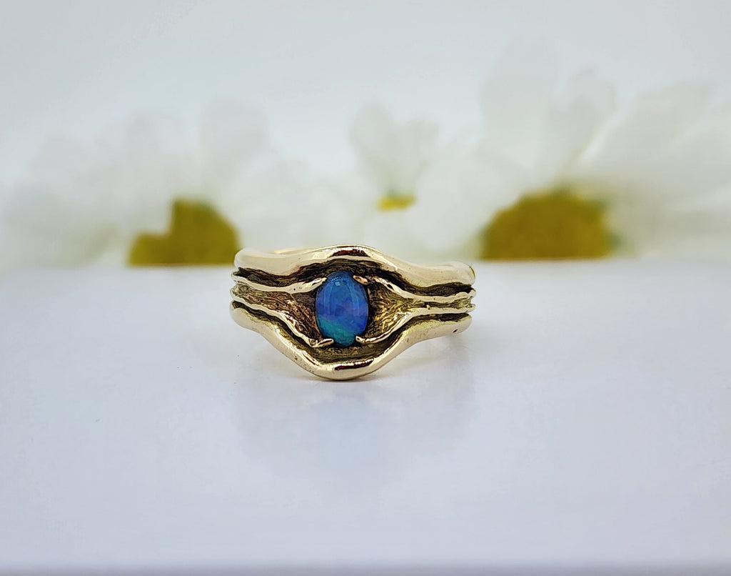 If you love an organic look, this ring is for you! A solid crafted ring of 14k yellow gold (7.00grams), no open back here! Set with a 5.87mmx4.15mm oval doublet Opal. Lots of color play with this Opal! While there is not antiquing on this ring, it has some interesting and dark patina! The ring measures 10.60mm at the top and tapers to a 5.35mm shank