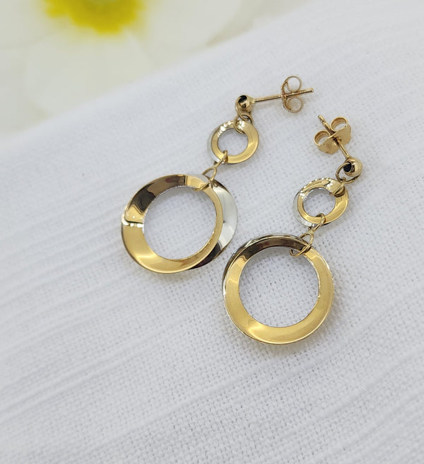 14k Two-Tone Gold Dangle Circle Earrings

These elegant dangle earrings are crafted in 14k white and yellow gold, featuring a modern double-circle design with beautiful movement. Polished ball studs lead to graduated open circles that catch the light effortlessly, offering a timeless yet contemporary look that transitions easily from day to evening.
Details:
Metal: 14k white and yellow gold
Style: Dangle earrings
Total weight: 3.00 grams
Length: 29.00mm from the ball stud
Width: 16.50mm (largest circle)