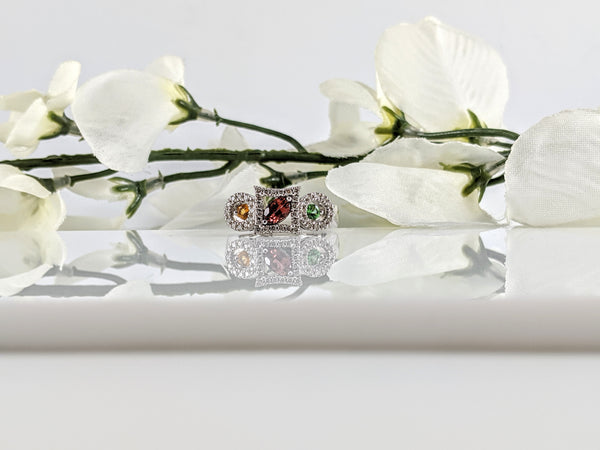 Constructed of 14K white gold, this ring is solid and features a great color combination and stone cuts. The center stone is a marquise cut Pink Tourmaline set diagonal in a square halo. On one side is a round cut Tsavorite Garnet and on the other side is a round cut Citrine. All gemstones have a halo of diamonds around them. If you are looking for something unique, this is certainly the ring for you. Finger size 7. $1200.00 