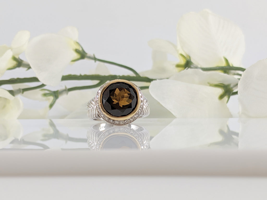 What a stunning ring! The warmth and glow of the beautiful Smoky Quartz is like a beacon of light calling you to port. This is no small stone either. Measuring just over 11mm, the stone is encircled by a halo of diamonds and 14k yellow gold. Finger size 7.  $275.00