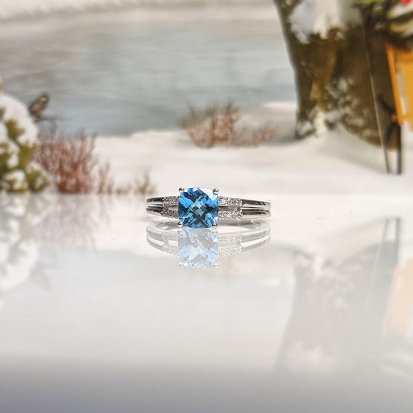 10K white gold and swiss blue topaz ring. Ring is set with a cushion cut 5x5mm topaz. .20cttw in round brilliant cut diamonds compliment this beautiful piece. Finger size 6.75. $990.00