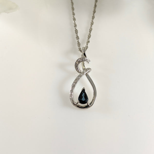This fabulous pendant is constructed of 14K white gold and contains a lovely 6x4mm blue Sapphire. Complimenting this stone are .10cttw in round brilliant cut diamonds. This pendant is long, measuring 28.00mm long and is hung an a 20" inch 14k white gold Singapore chain. $1050.00
