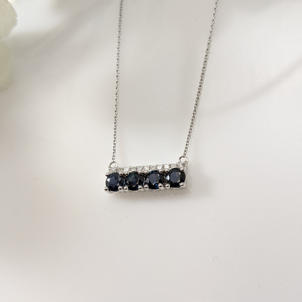 If you are a fan of the bar necklaces, this is the necklace for you! Both contemporary and elegant this stunning necklace is set with four round natural blue Sapphires and 1/20th carats of diamond. Pendant measures 14.50mm horizontally. Comes with the chain. 10k white gold. 18" inches. $550.00