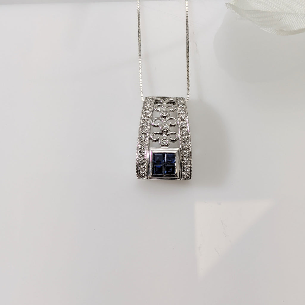 Crafted in 14K white gold, this pendant has four square cut blue Sapphires set together to give the illusion of a 5mm stone. A .25cttw in round brilliant cut diamonds and beautiful filigree make this pendant a stand out! Just over 14mm in length. Tapers from top to bottom. Chain sold separately. $425.00